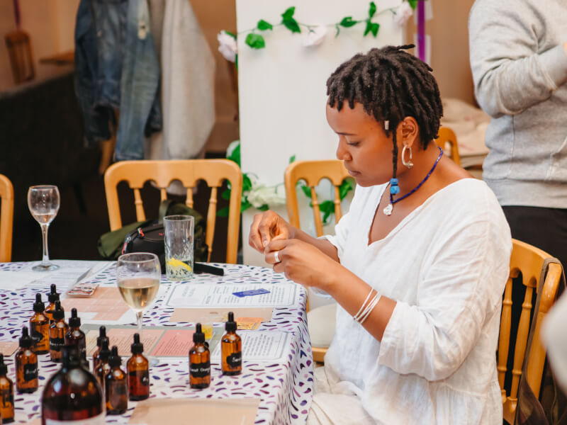 Woman sitting a table with amber essential oil bottles in front of her